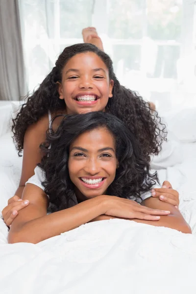 Sonrientes madre e hija posando juntas en la cama —  Fotos de Stock