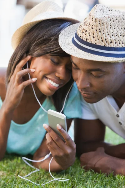 Lyckliga unga paret lyssnar på musik på gräset — Stockfoto