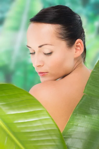 Prachtige naakt brunette poseren met groene bladeren — Stockfoto