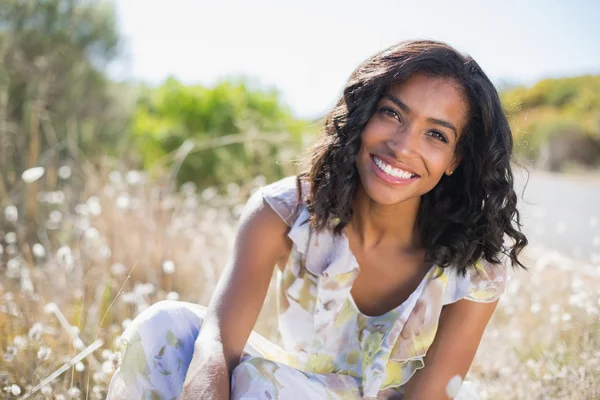 Mujer bonita feliz sentado en la hierba en vestido floral — Foto de Stock