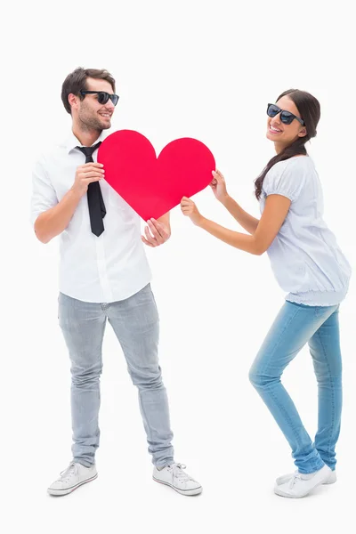 Couple hipster souriant à la caméra tenant un cœur — Photo