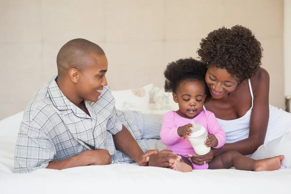 Happy parents and baby girl sitting on bed together — Stock Photo, Image