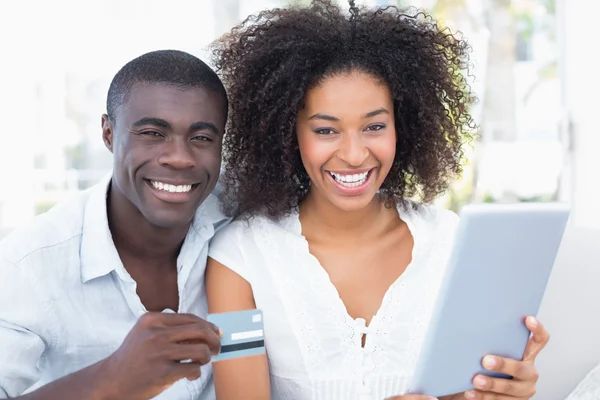 Atractiva pareja usando la tableta juntos en el sofá para comprar en línea —  Fotos de Stock