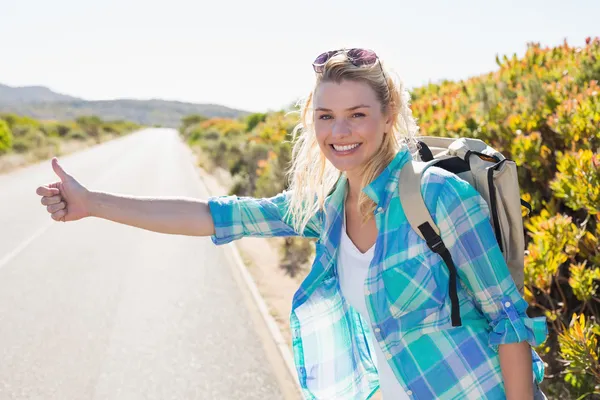 Blonde hitch hiking op landelijke weg — Stockfoto
