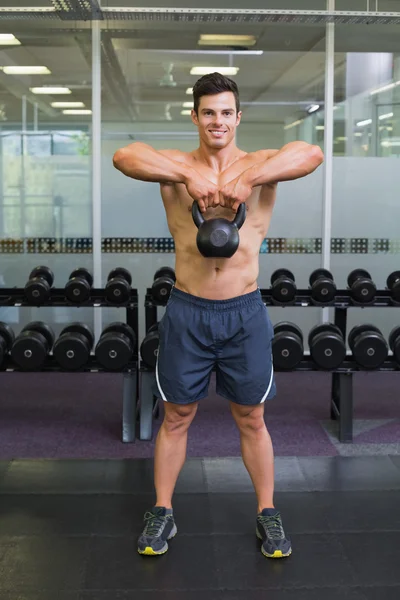 Мускулистый мужчина поднимает колокол в спортзале — стоковое фото