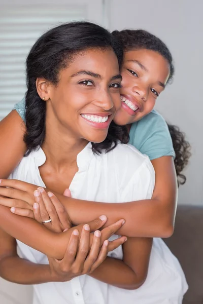 Mãe e filha felizes abraçando no sofá — Fotografia de Stock