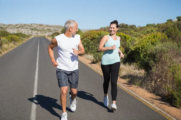 Fit couple running on the open road together — Stock Photo, Image