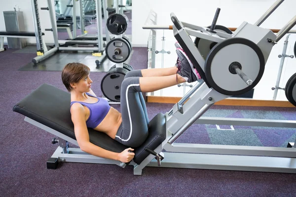 Fit brunette using weights machine for legs — Stock Photo, Image