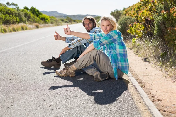 Couple sitting on road hitching lift — Stock Photo, Image