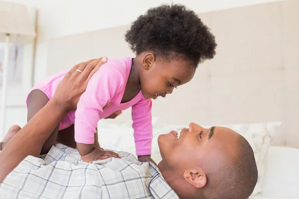 Padre y niña acostados juntos en la cama — Foto de Stock