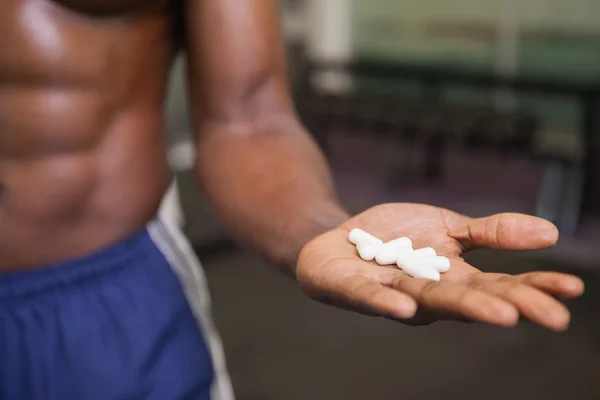 Muscular hombre sosteniendo píldoras vitamínicas en la mano — Foto de Stock