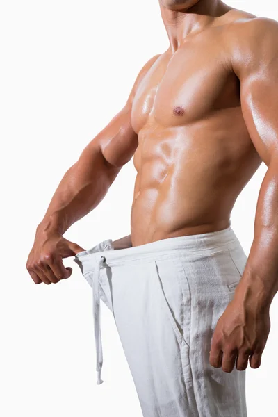 Corte médio de um homem musculoso em uma calça de tamanho superior — Fotografia de Stock