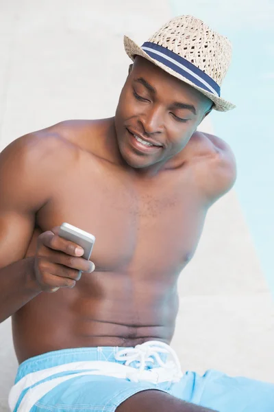 Homme souriant textos au téléphone près de la piscine — Photo