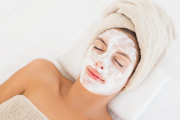 Mulher atraente ter creme branco em seu rosto no centro de spa — Fotografia de Stock