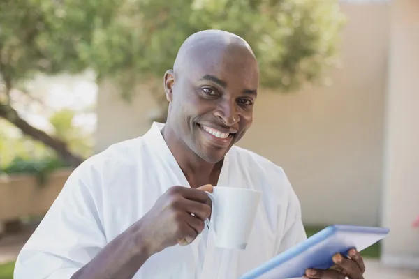 Schöner Mann im Bademantel mit Tablette beim Frühstück draußen — Stockfoto