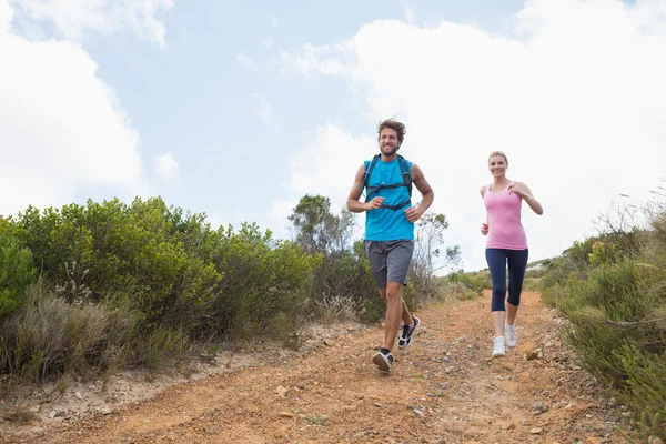 Coppia jogging giù sentiero di montagna — Foto Stock