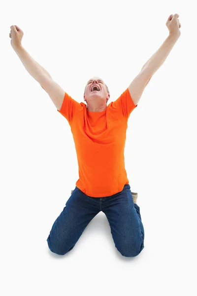 Mature man in orange tshirt cheering while kneeling — Stock Photo, Image