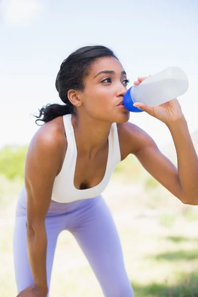 Подтянутая женщина пьет воду из спортивной бутылки — стоковое фото