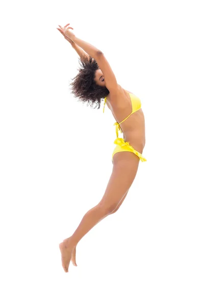 Подходящая девушка в желтом бикини прыгает и растягивается — стоковое фото