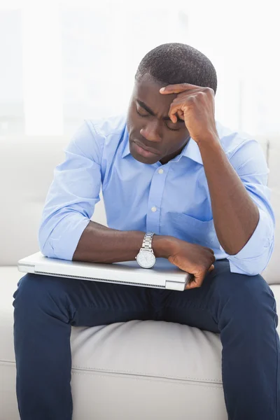 Empresário estressado recebendo uma dor de cabeça segurando seu laptop — Fotografia de Stock