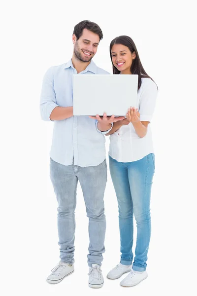 Atractiva pareja joven sosteniendo su portátil — Foto de Stock