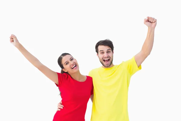 Entusiasmado casal torcendo em tshirts vermelhas e amarelas — Fotografia de Stock