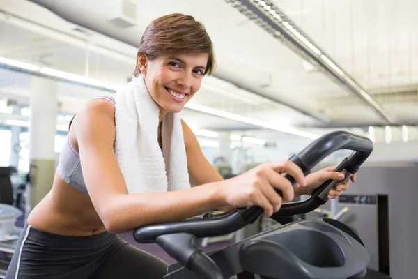 Ajuste morena sonriente haciendo ejercicio en la bicicleta estática — Foto de Stock