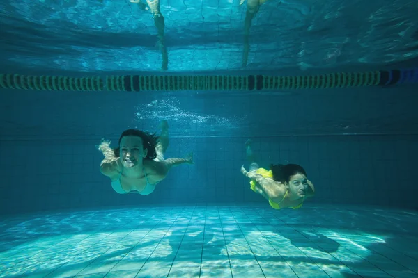 Hübsche Freunde lächeln und schwimmen unter Wasser — Stockfoto