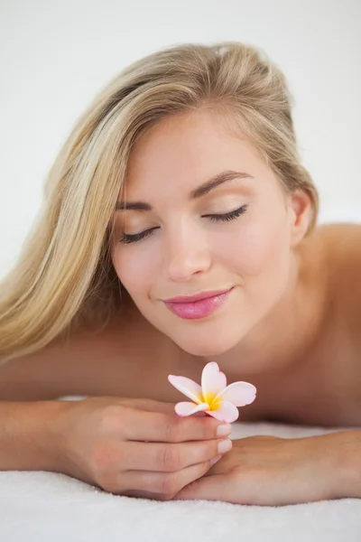 Mooie blonde liggend op een massagetafel ruiken bloem — Stockfoto