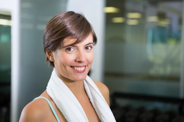 Fit brunette smiling at camera with towel around shoulders — Stock Photo, Image