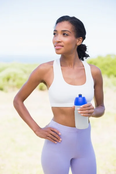 Fit woman holding sports bottle smiling — Stock Photo, Image