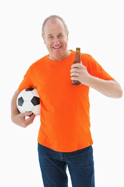 Hombre maduro en camiseta naranja sosteniendo fútbol y cerveza — Foto de Stock