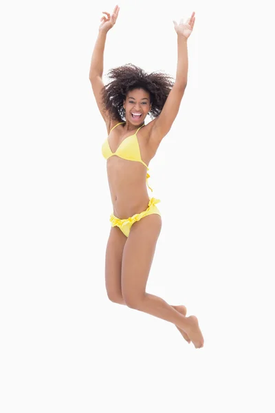 Athletic girl in yellow bikini jumping and smiling at camera — Stockfoto