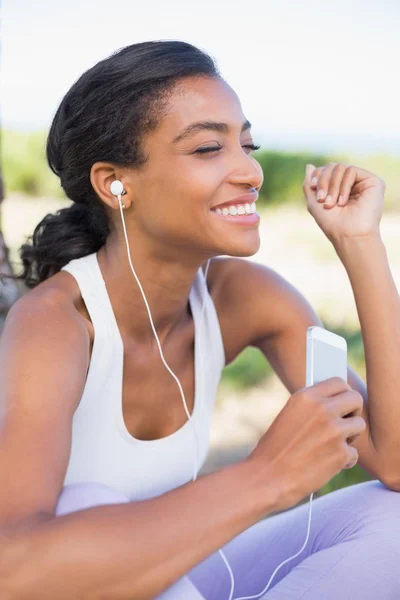 Fitte Frau im Sitzen und Musik hören — Stockfoto