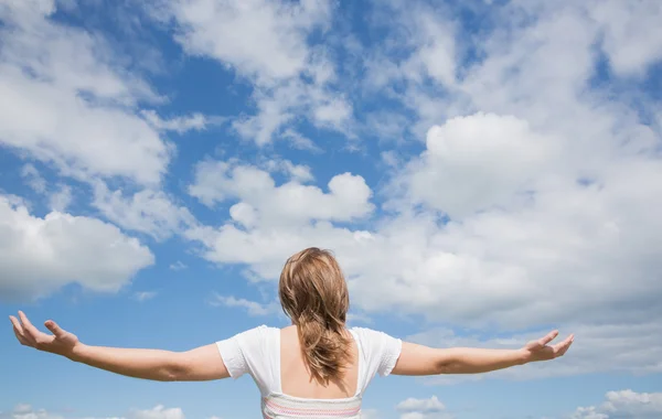 Mujer con brazos extendidos contra el cielo azul y las nubes — Foto de Stock