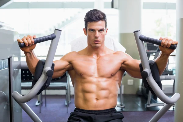 Gespierde man aan het werk op fitness machine op de sportschool — Stockfoto