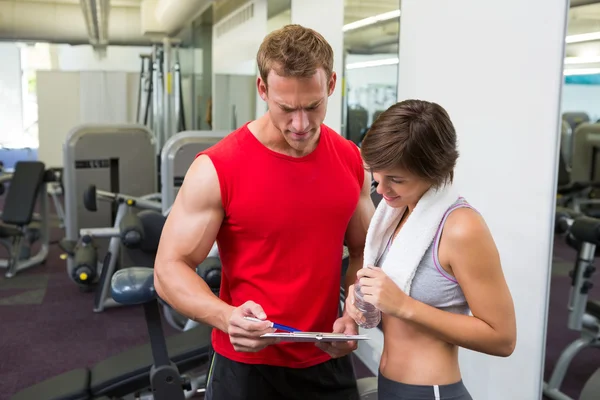 Bello personal trainer con il suo cliente guardando appunti — Foto Stock