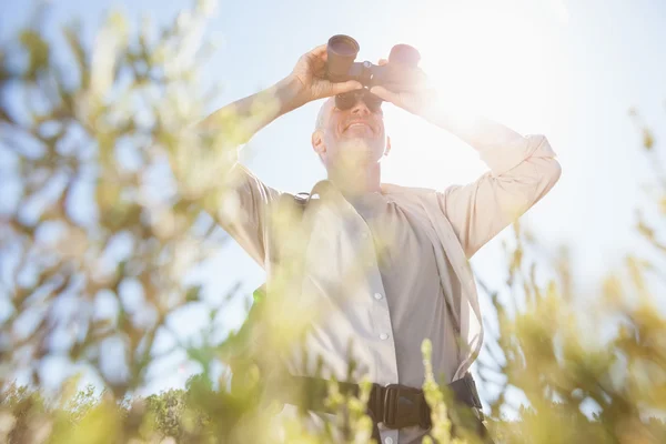 Randonneur debout sur le sentier de campagne regardant à travers les jumelles — Photo