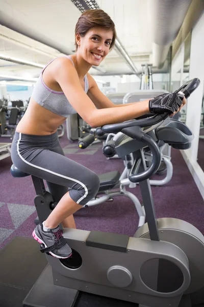 Fit mujer sonriente haciendo ejercicio en la bicicleta estática —  Fotos de Stock