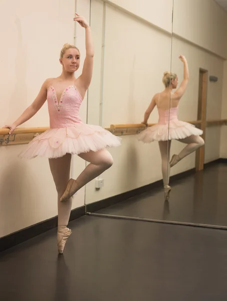 Beautiful ballerina standing en pointe with the barre — Stock Photo, Image