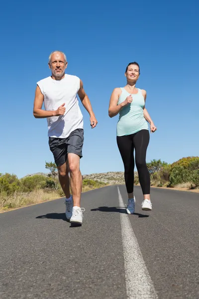 Fit couple running on the open road together — Stock Photo, Image