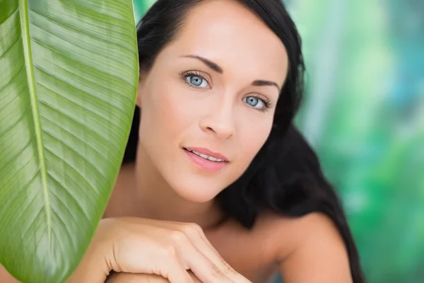 Krásná nahá bruneta se usmívá na fotoaparát s zelený list — Stock fotografie