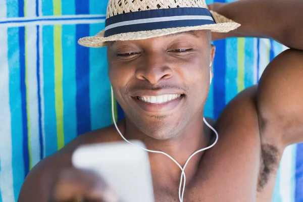 Hombre guapo sin camisa escuchando música junto a la piscina — Foto de Stock