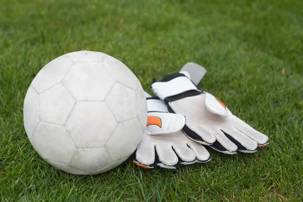 Goalkeeping gloves and football on pitch — Stock Photo, Image