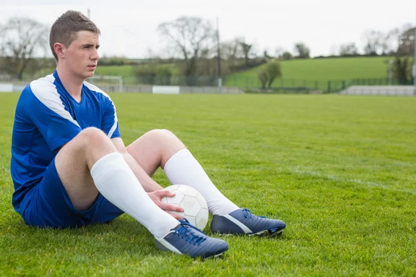 Jugador de fútbol en azul tomando un descanso en el campo — Foto de Stock