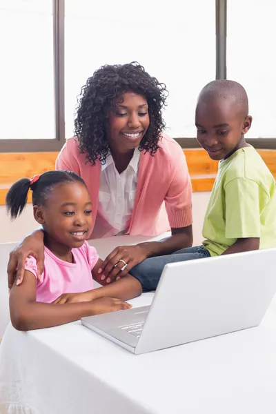 Schattig broers en zussen met behulp van laptop samen met moeder — Stockfoto