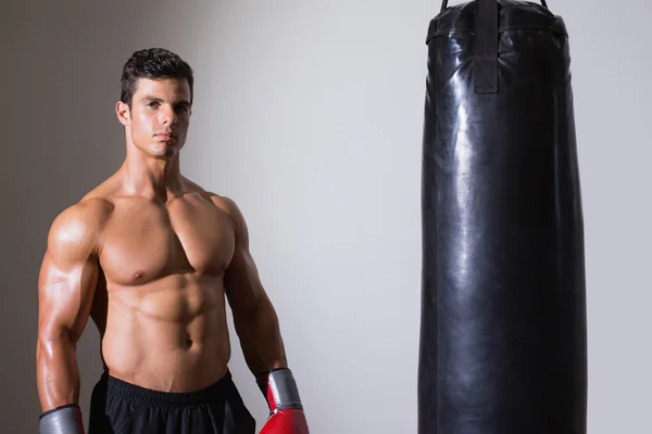 Porträt eines hemdlosen muskulösen Boxers mit Boxsack — Stockfoto