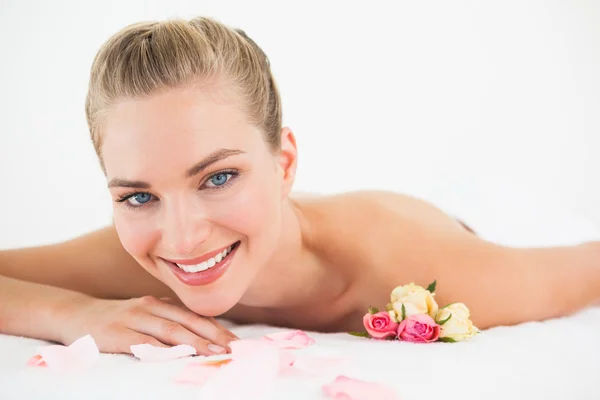 Mooie blonde liggend op een massagetafel met rozenblaadjes — Stockfoto