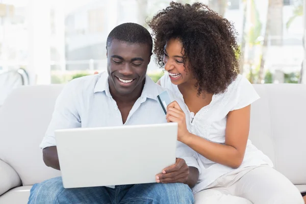 Casal atraente usando laptop juntos no sofá para comprar on-line — Fotografia de Stock