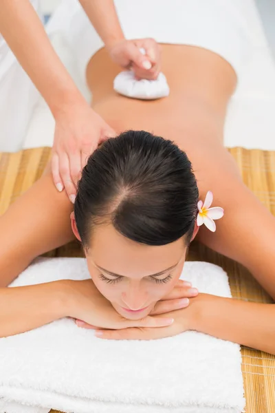 Peaceful brunette enjoying a herbal compress massage — Stock Photo, Image